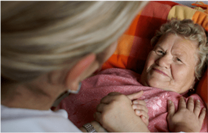 Frau vom Pflegedienst kümmert sich um bettlägerige ältere Frau